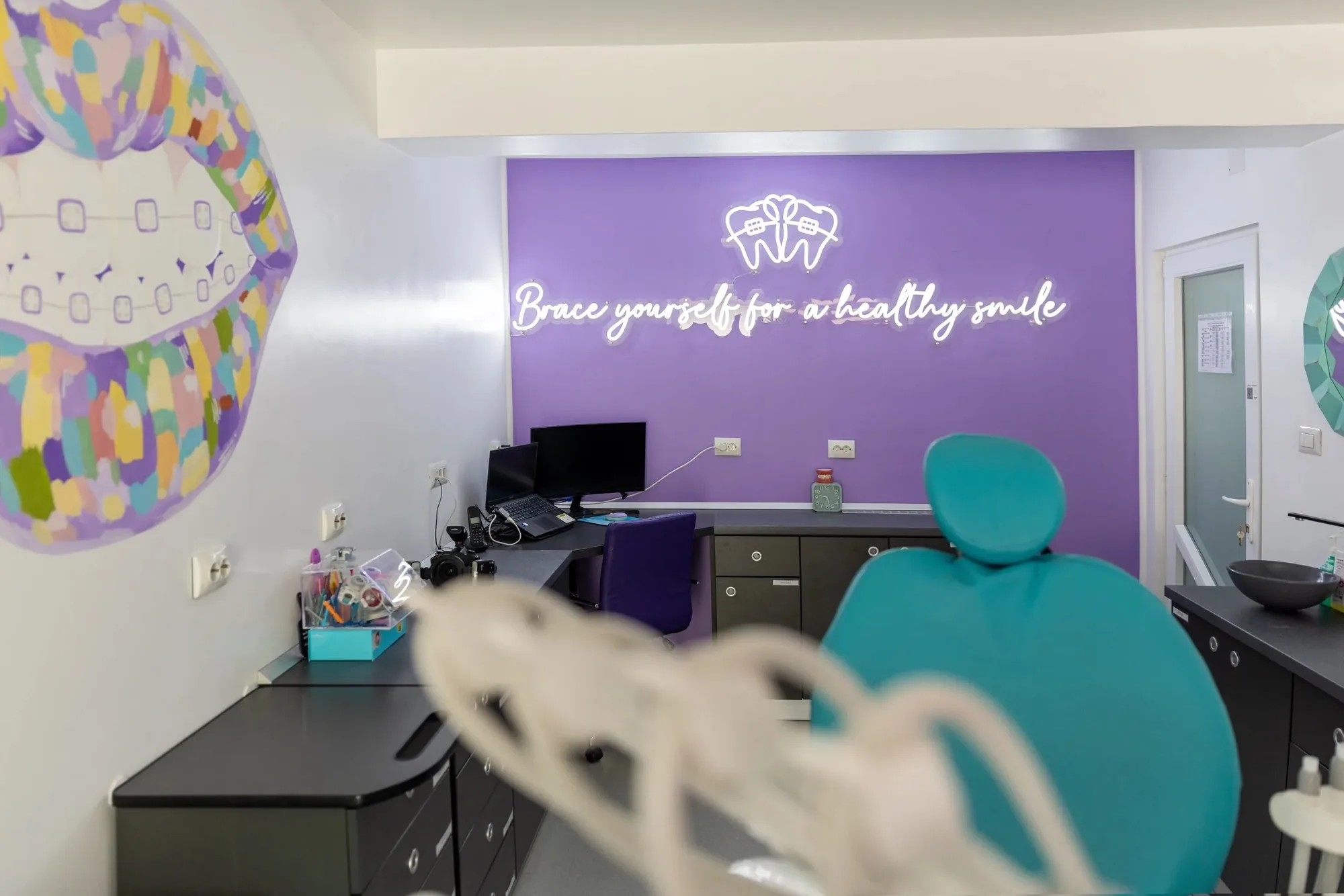 Cabinet la Stomdas, cu neonul „Brace yourself for a healthy smile” pe perete
